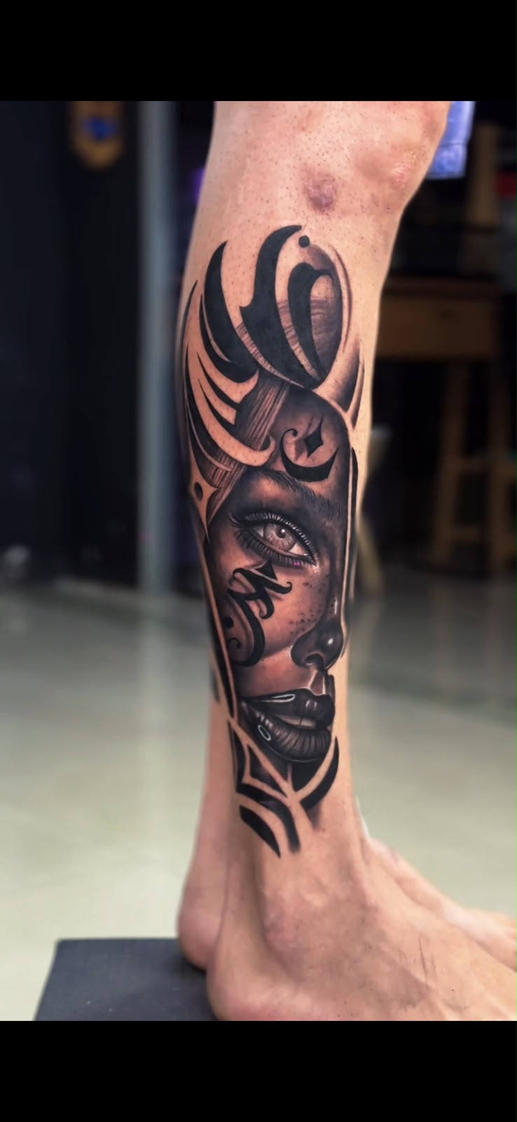 Tatuagem de rosto feminino com elementos abstratos na perna — Tainan Santos